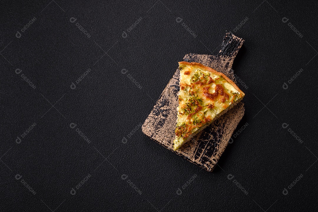 Deliciosa quiche com brócolis, queijo, frango, especiarias e ervas sobre um fundo escuro de concreto