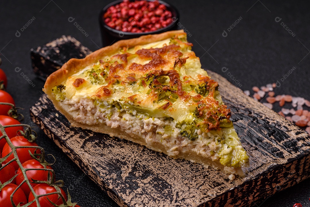 Deliciosa quiche com brócolis, queijo, frango, especiarias e ervas sobre um fundo escuro de concreto