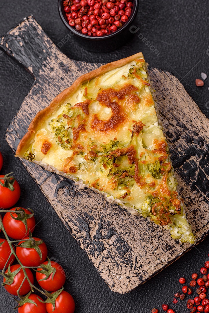 Deliciosa quiche com brócolis, queijo, frango, especiarias e ervas sobre um fundo escuro de concreto