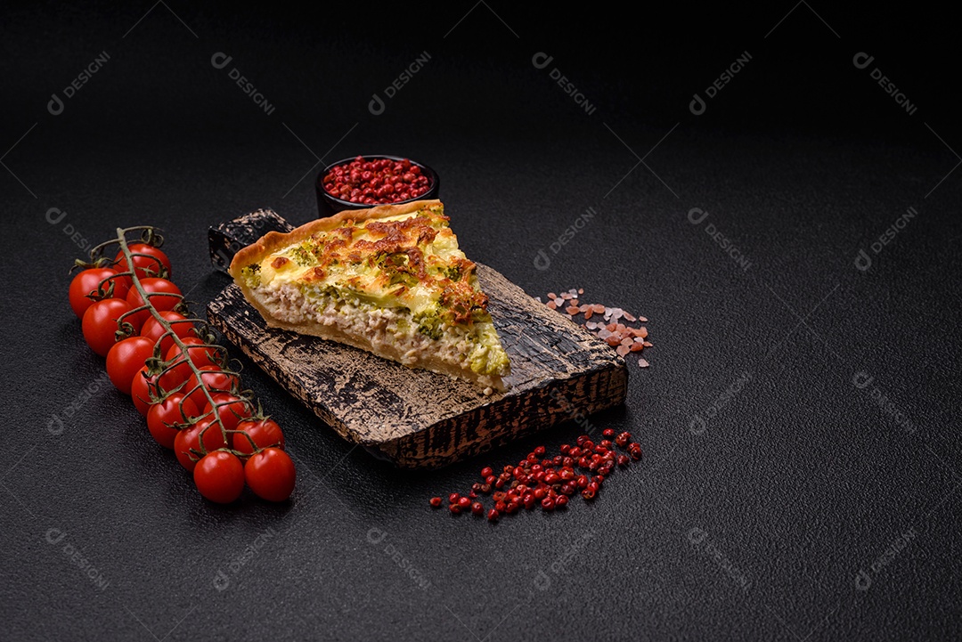 Deliciosa quiche com brócolis, queijo, frango, especiarias e ervas sobre um fundo escuro de concreto