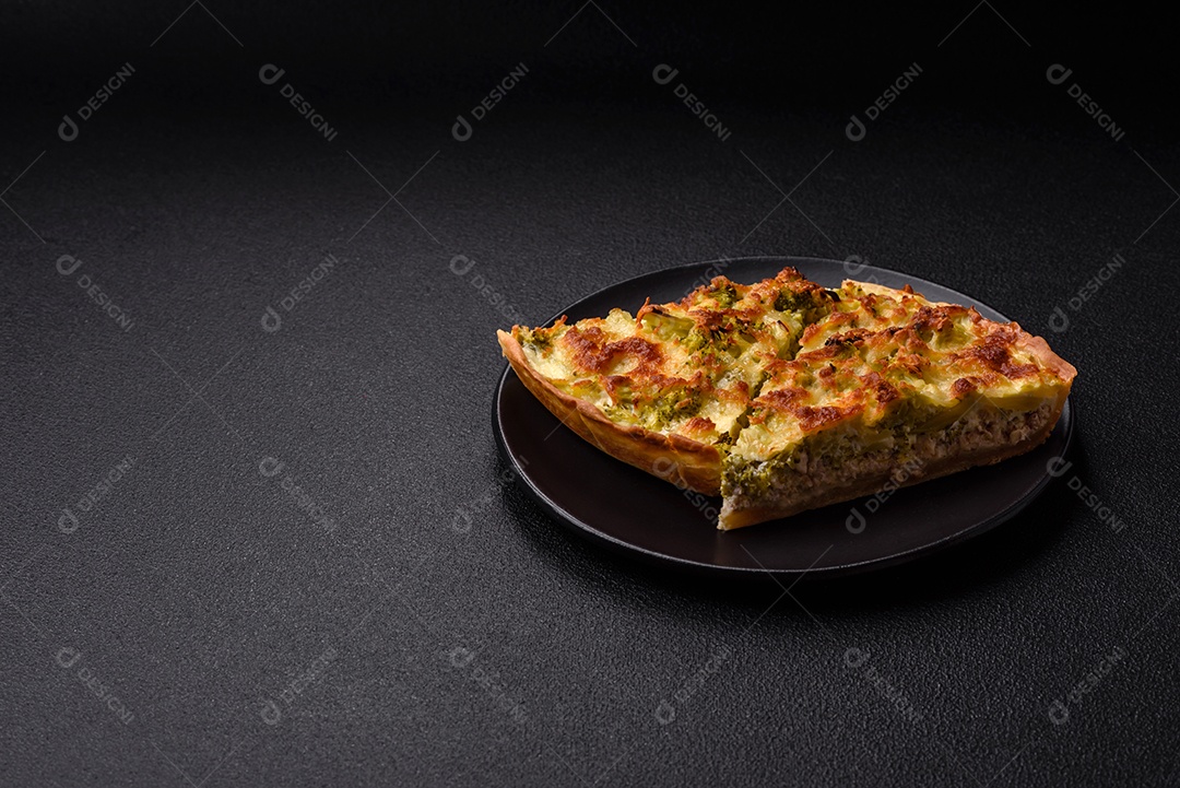 Deliciosa quiche com brócolis, queijo, frango, especiarias e ervas sobre um fundo escuro de concreto