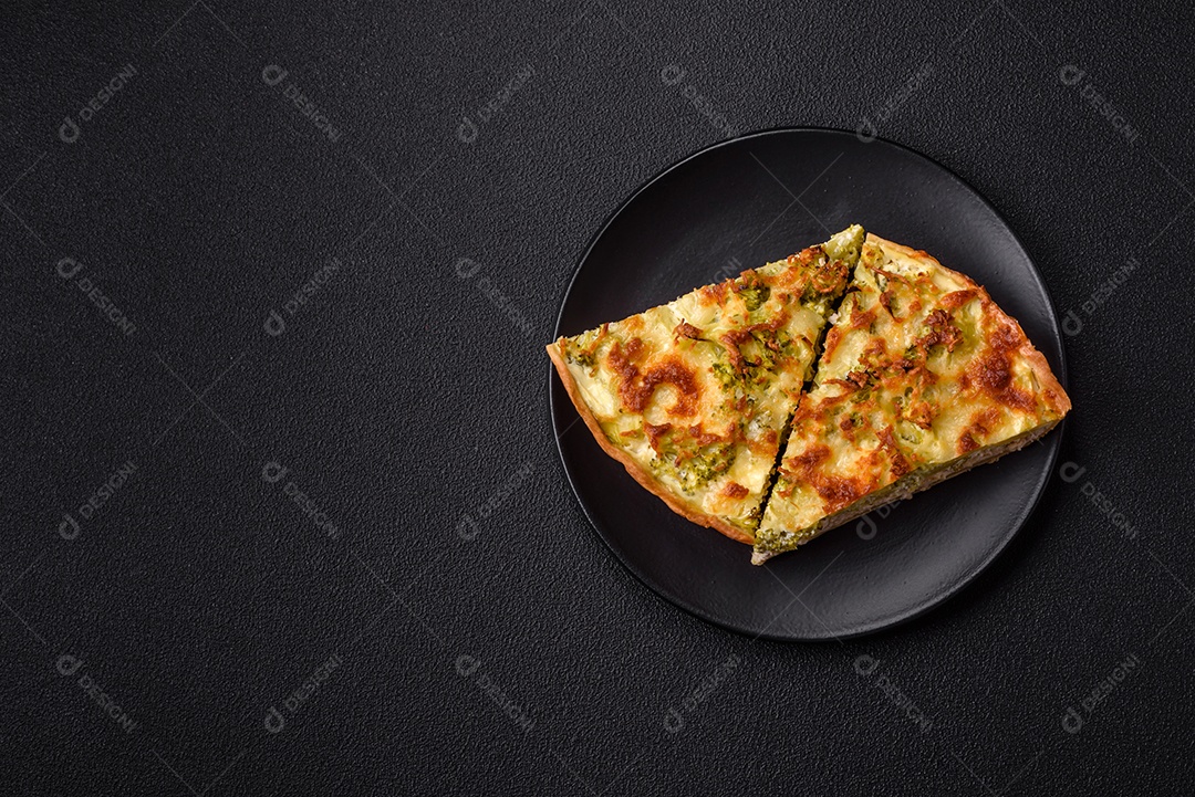 Deliciosa quiche com brócolis, queijo, frango, especiarias e ervas sobre um fundo escuro de concreto