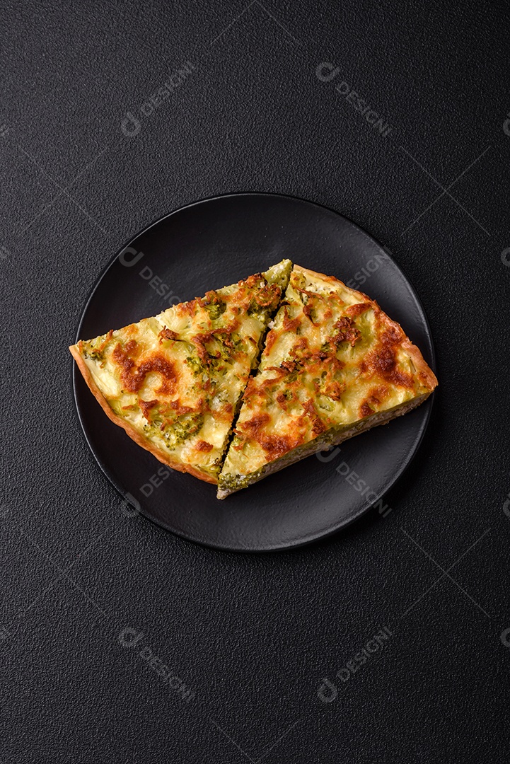 Deliciosa quiche com brócolis, queijo, frango, especiarias e ervas sobre um fundo escuro de concreto