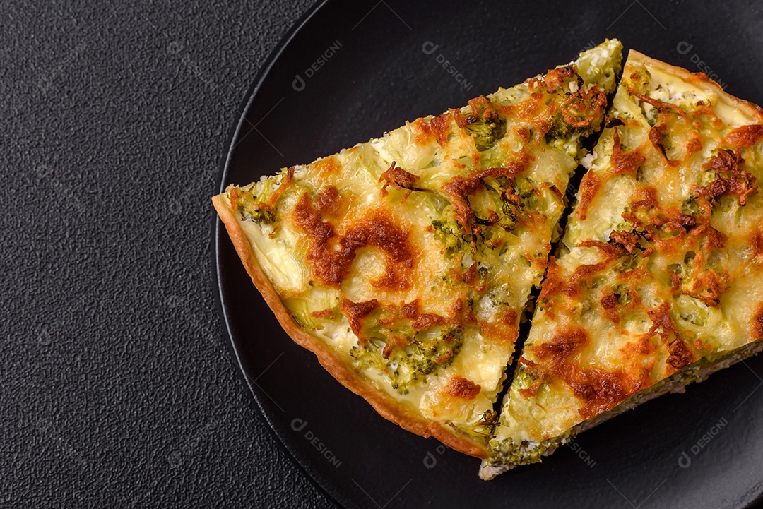 Deliciosa quiche com brócolis, queijo, frango, especiarias e ervas sobre um fundo escuro de concreto