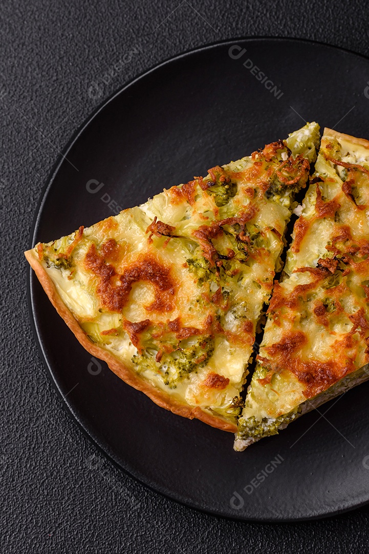 Deliciosa quiche com brócolis, queijo, frango, especiarias e ervas sobre um fundo escuro de concreto