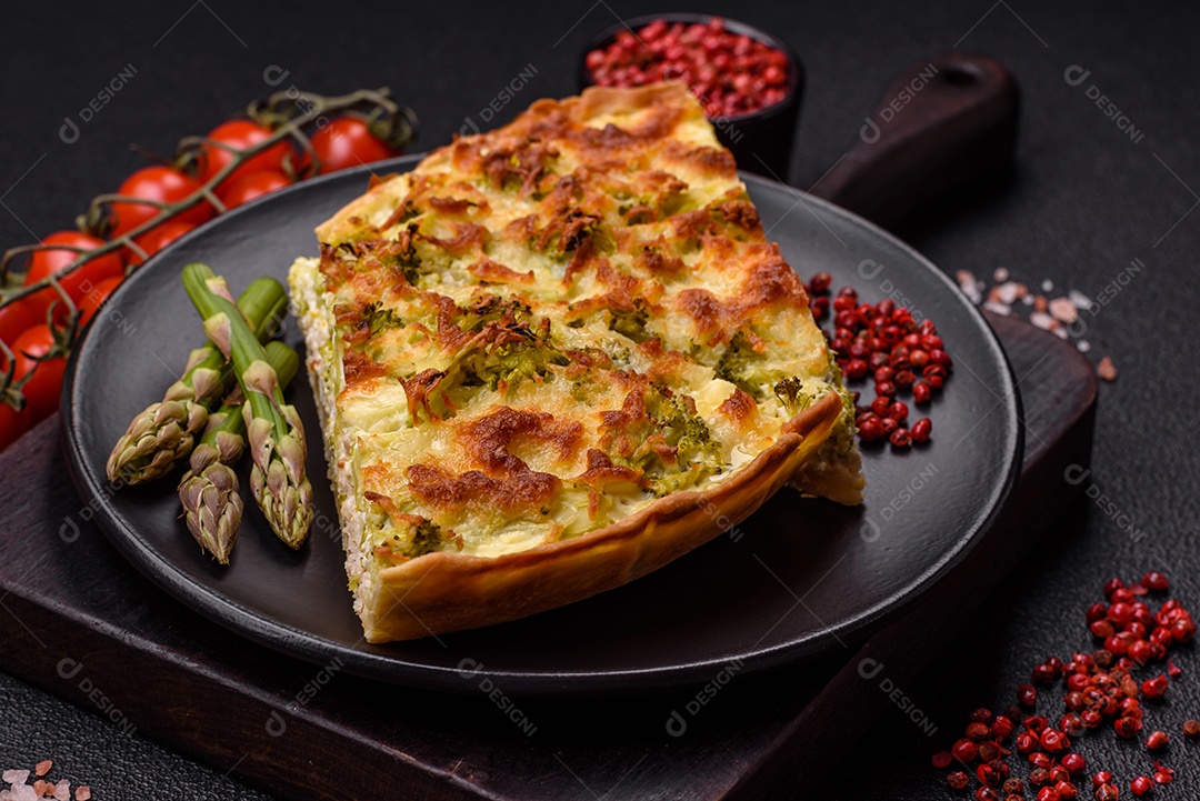 Deliciosa quiche com brócolis, queijo, frango, especiarias e ervas sobre um fundo escuro de concreto