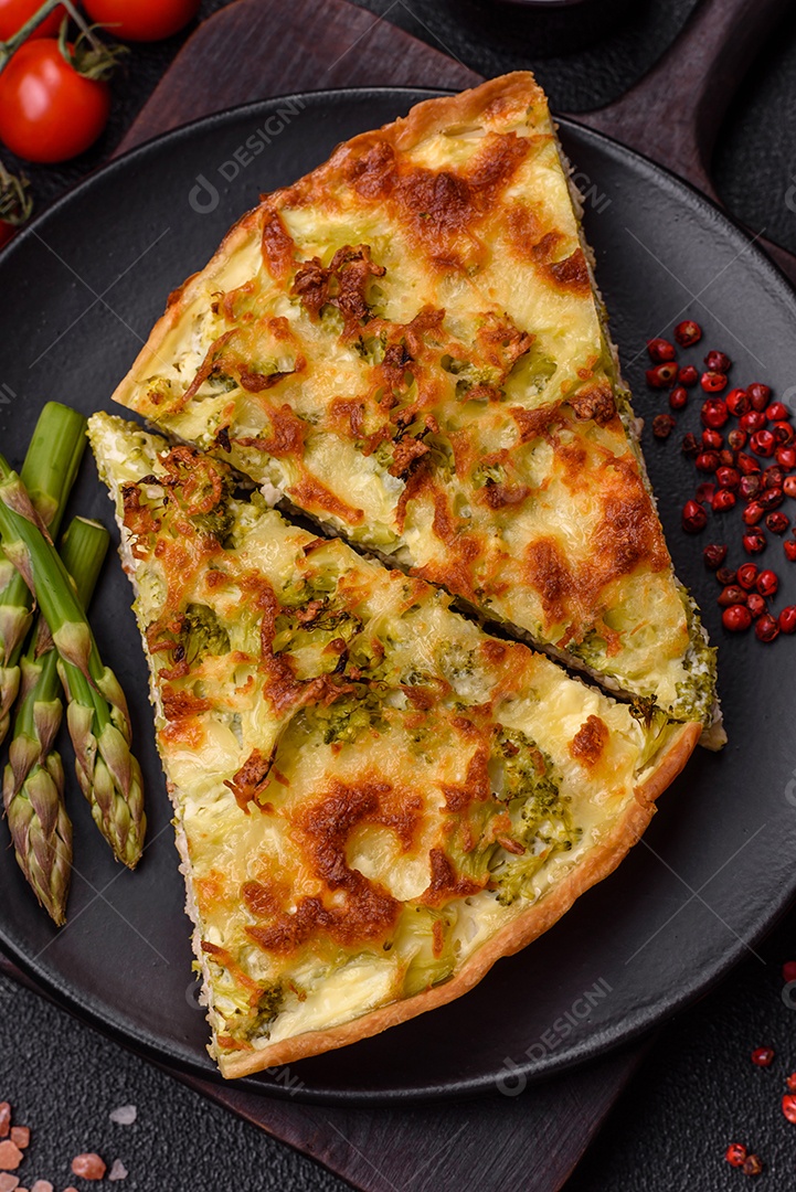 Deliciosa quiche com brócolis, queijo, frango, especiarias e ervas sobre um fundo escuro de concreto