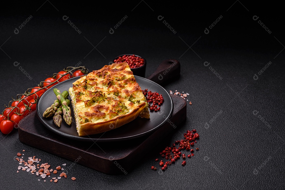 Deliciosa quiche com brócolis, queijo, frango, especiarias e ervas sobre um fundo escuro de concreto