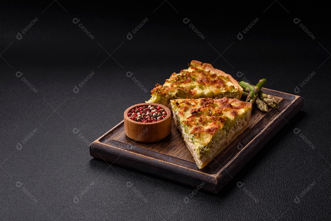 Deliciosa quiche com brócolis, queijo, frango, especiarias e ervas sobre um fundo escuro de concreto