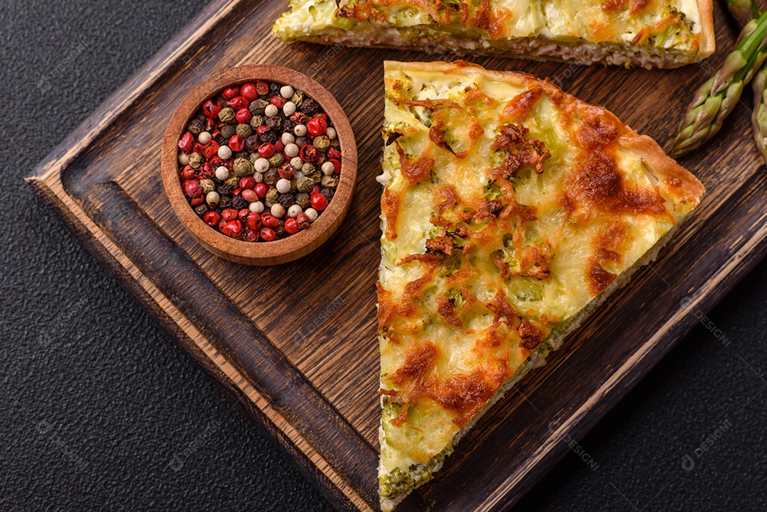 Deliciosa quiche com brócolis, queijo, frango, especiarias e ervas sobre um fundo escuro de concreto