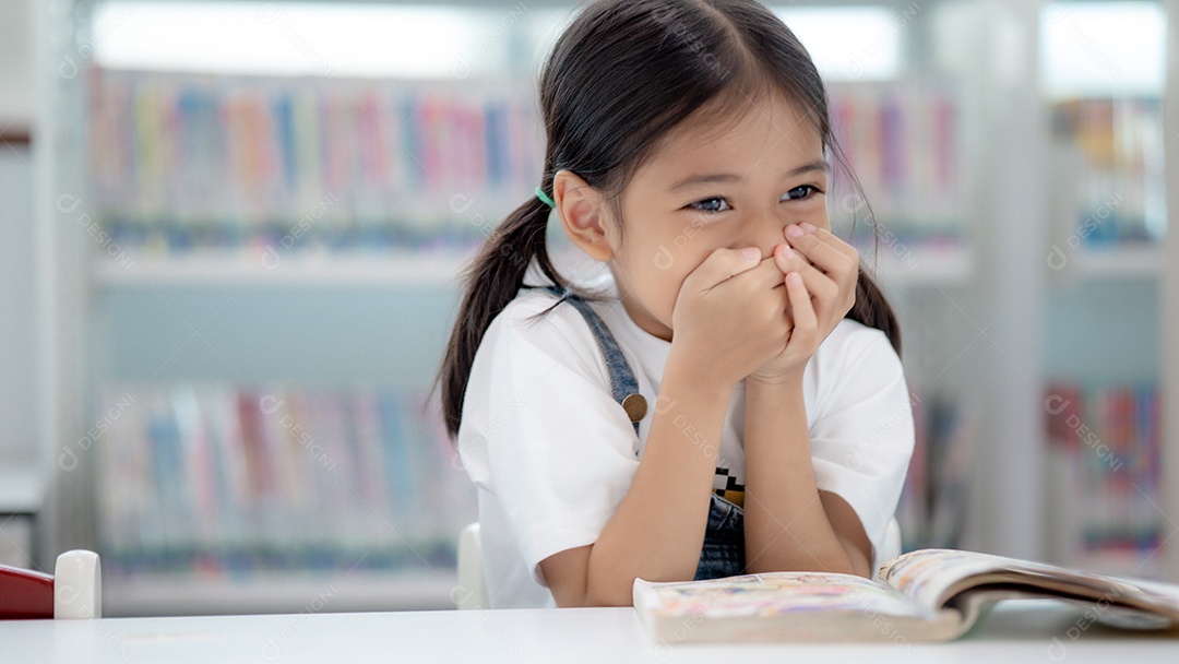 Garotinha sorrindo e lendo um livro na biblioteca