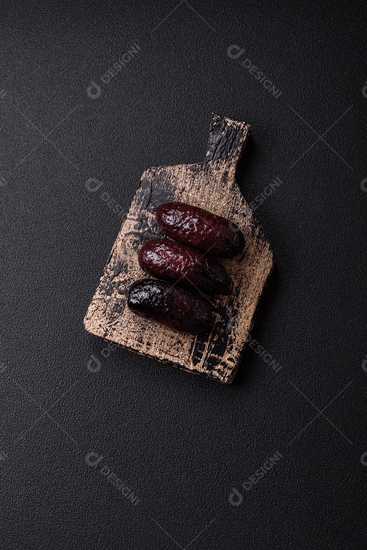 Delicioso chouriço preto ou morcela com especiarias e ervas grelhadas sobre fundo de concreto preto