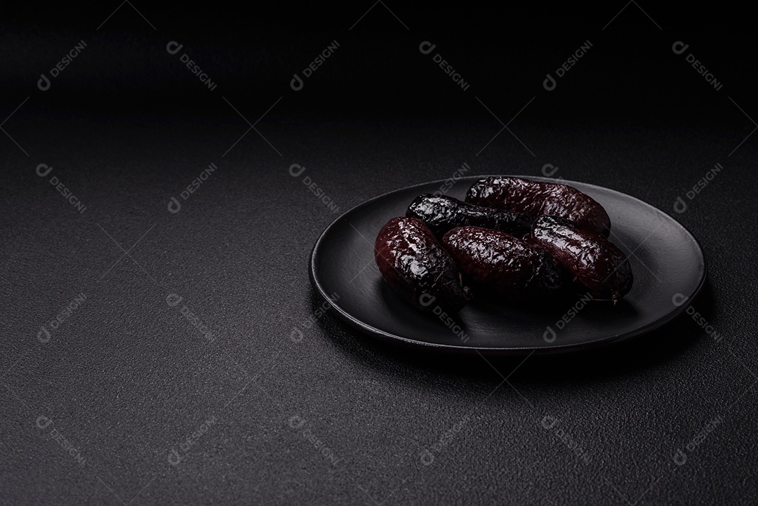 Delicioso chouriço preto ou morcela com especiarias e ervas grelhadas sobre fundo de concreto preto