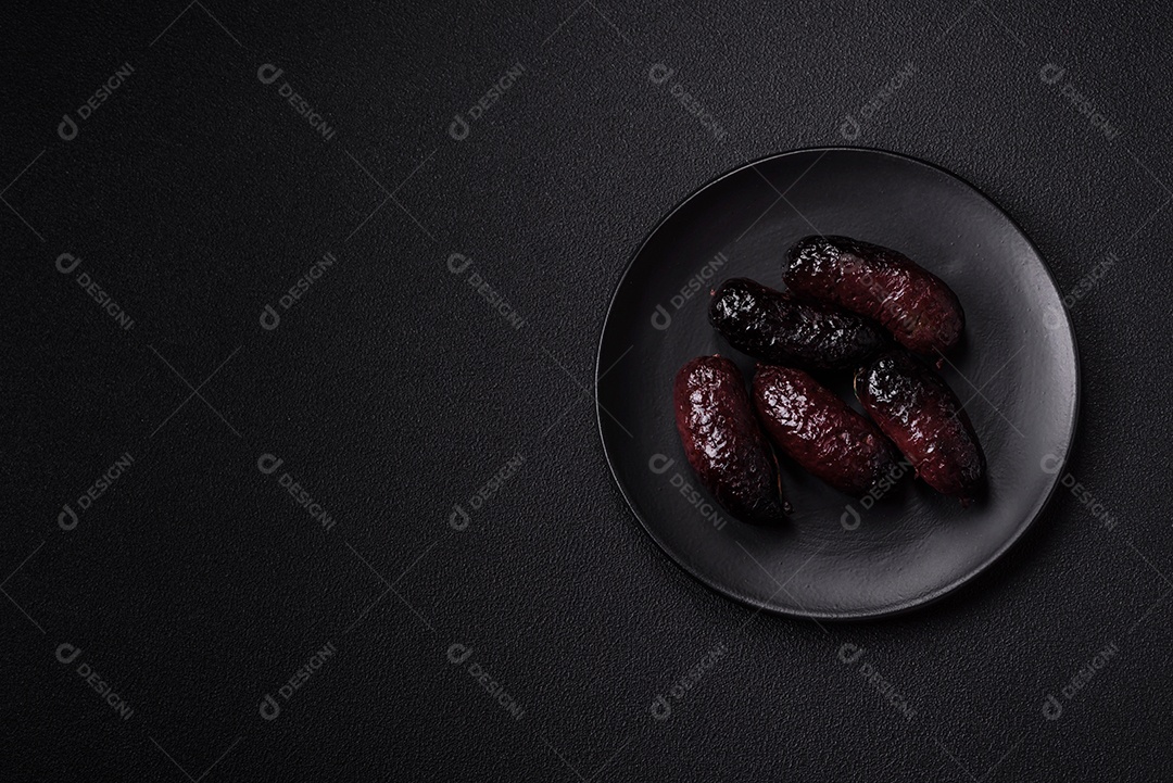 Delicioso chouriço preto ou morcela com especiarias e ervas grelhadas sobre fundo de concreto preto