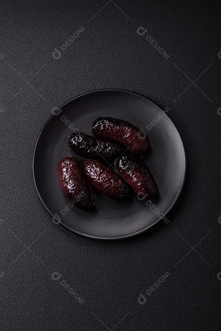 Delicioso chouriço preto ou morcela com especiarias e ervas grelhadas sobre fundo de concreto preto