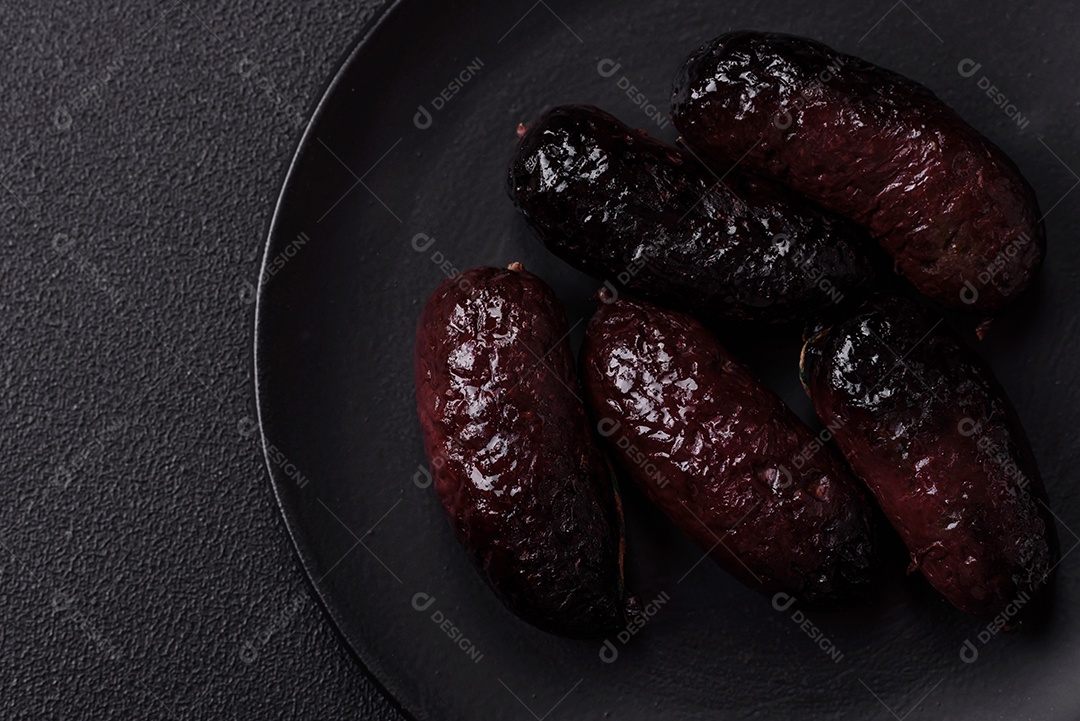 Delicioso chouriço preto ou morcela com especiarias e ervas grelhadas sobre fundo de concreto preto