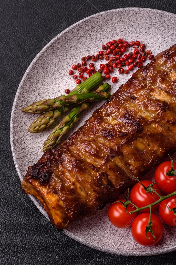 Deliciosas costelas grelhadas suculentas com mel e molho de mostarda com sal, especiarias e ervas sobre um fundo escuro de concreto