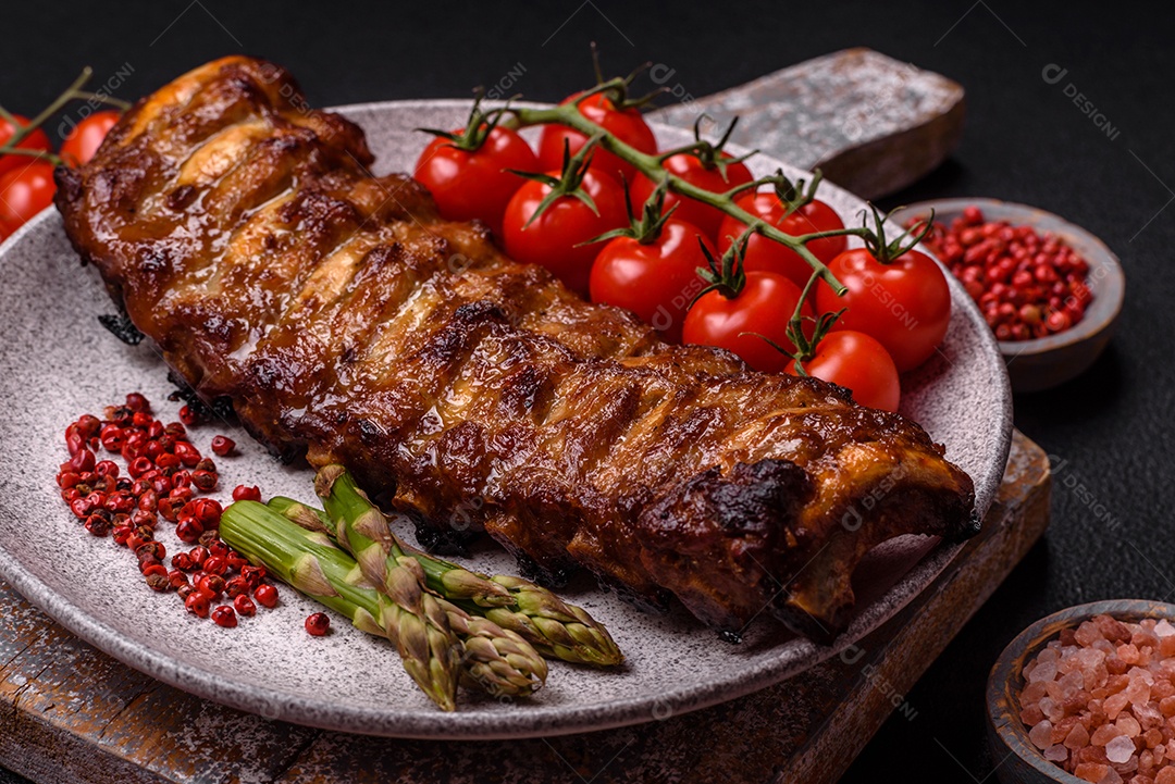 Deliciosas costelas grelhadas suculentas com mel e molho de mostarda com sal, especiarias e ervas sobre um fundo escuro de concreto