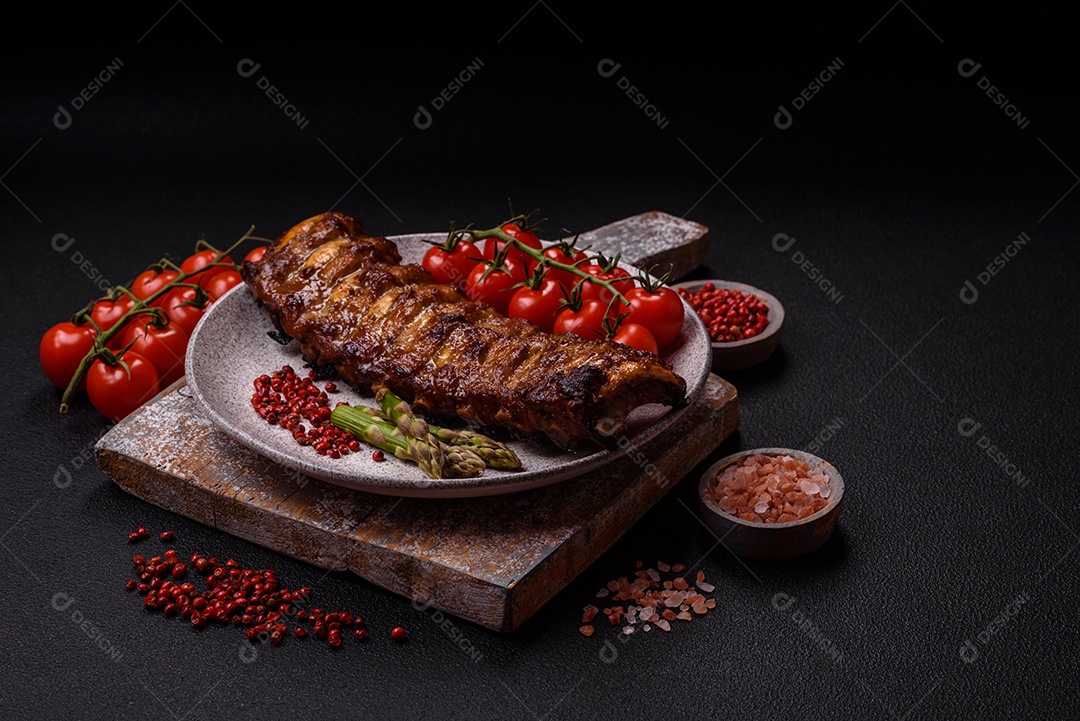 Deliciosas costelas grelhadas suculentas com mel e molho de mostarda com sal, especiarias e ervas sobre um fundo escuro de concreto