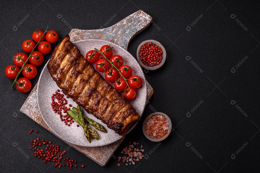 Deliciosas costelas grelhadas suculentas com mel e molho de mostarda com sal, especiarias e ervas sobre um fundo escuro de concreto