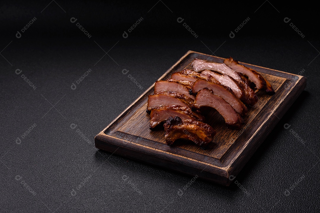 Deliciosas costelas grelhadas suculentas com mel e molho de mostarda com sal, especiarias e ervas sobre um fundo escuro de concreto