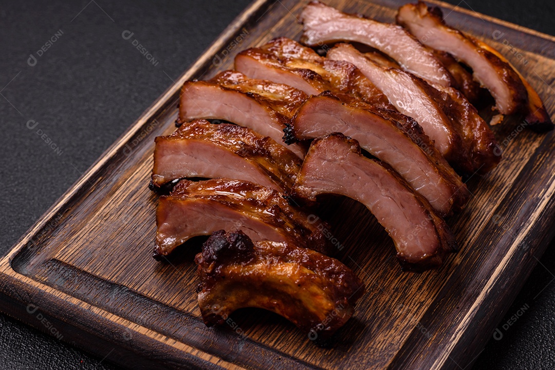 Deliciosas costelas grelhadas suculentas com mel e molho de mostarda com sal, especiarias e ervas sobre um fundo escuro de concreto