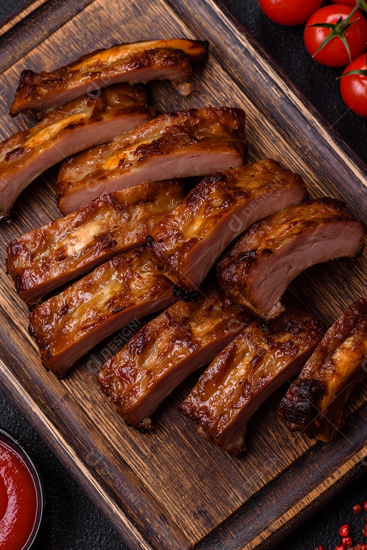 Deliciosas costelas grelhadas suculentas com mel e molho de mostarda com sal, especiarias e ervas sobre um fundo escuro de concreto