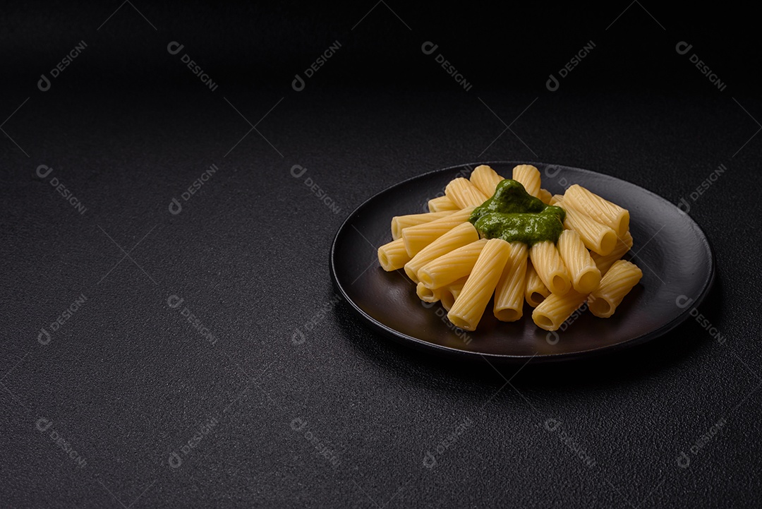 Deliciosa massa com molho de espinafre, azeite e queijo parmesão com sal, especiarias e ervas sobre fundo escuro de concreto