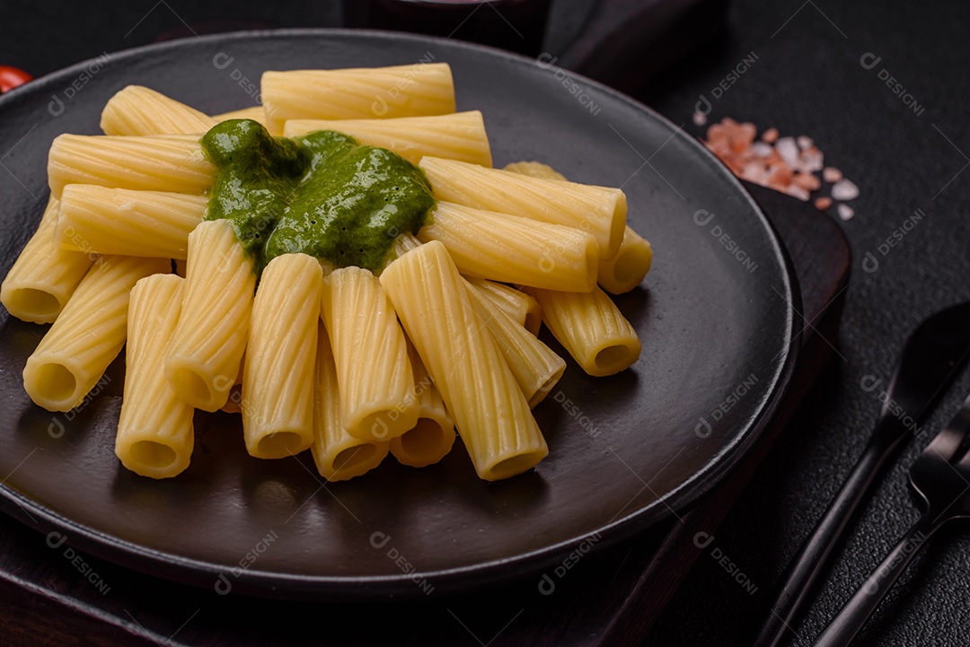 Deliciosa massa com molho de espinafre, azeite e queijo parmesão com sal, especiarias e ervas sobre fundo escuro de concreto