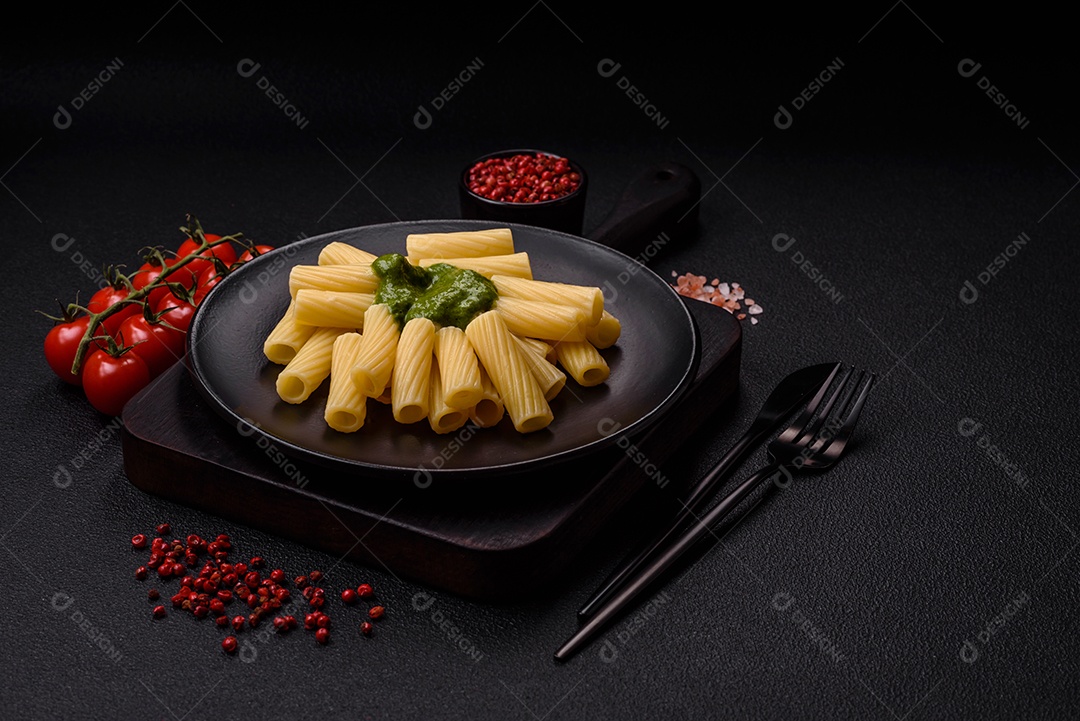 Deliciosa massa com molho de espinafre, azeite e queijo parmesão com sal, especiarias e ervas sobre fundo escuro de concreto