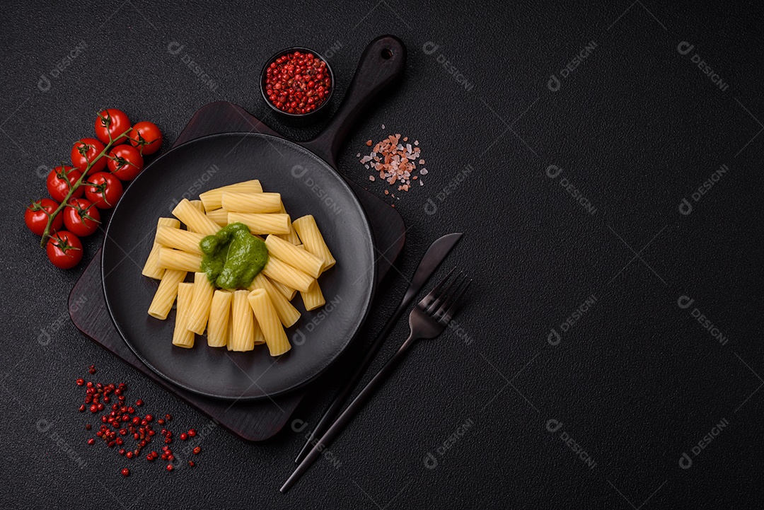 Deliciosa massa com molho de espinafre, azeite e queijo parmesão com sal, especiarias e ervas sobre fundo escuro de concreto