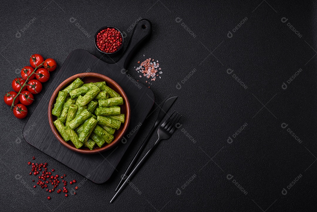 Deliciosa massa com molho de espinafre, azeite e queijo parmesão com sal, especiarias e ervas sobre fundo escuro de concreto