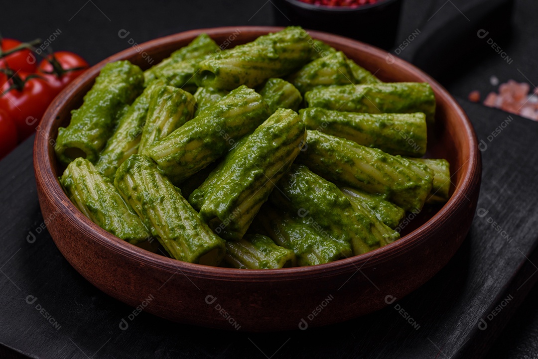 Deliciosa massa com molho de espinafre, azeite e queijo parmesão com sal, especiarias e ervas sobre fundo escuro de concreto