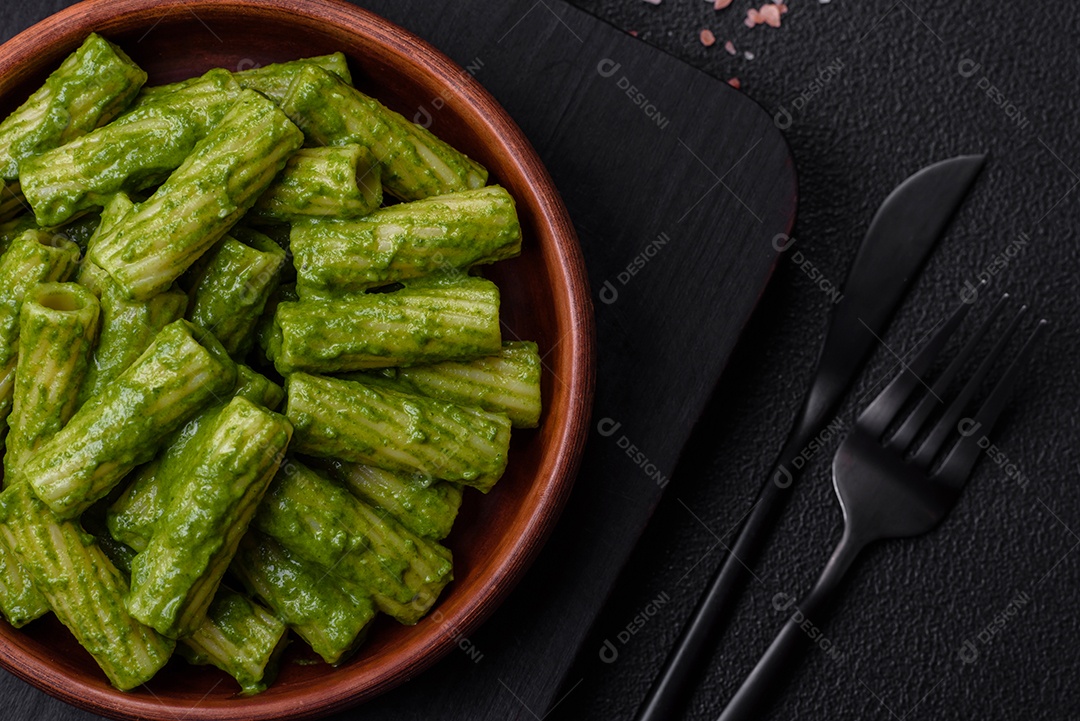 Deliciosa massa com molho de espinafre, azeite e queijo parmesão com sal, especiarias e ervas sobre fundo escuro de concreto