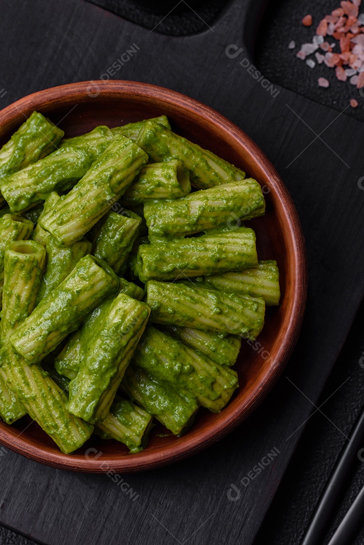 Deliciosa massa com molho de espinafre, azeite e queijo parmesão com sal, especiarias e ervas sobre fundo escuro de concreto