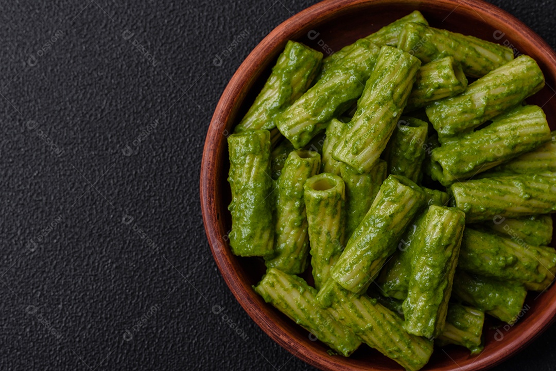 Deliciosa massa com molho de espinafre, azeite e queijo parmesão com sal, especiarias e ervas sobre fundo escuro de concreto