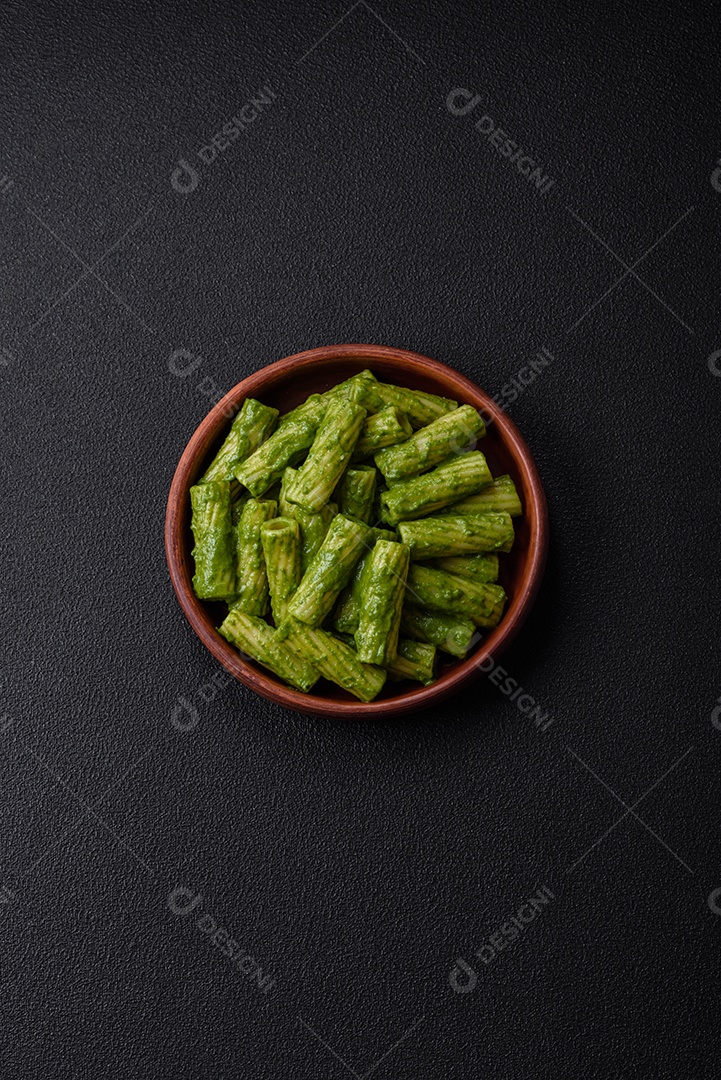 Deliciosa massa com molho de espinafre, azeite e queijo parmesão com sal, especiarias e ervas sobre fundo escuro de concreto
