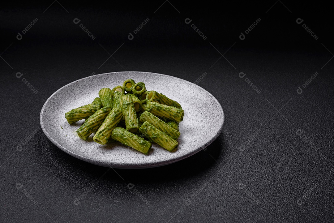 Deliciosa massa com molho de espinafre, azeite e queijo parmesão com sal, especiarias e ervas sobre fundo escuro de concreto