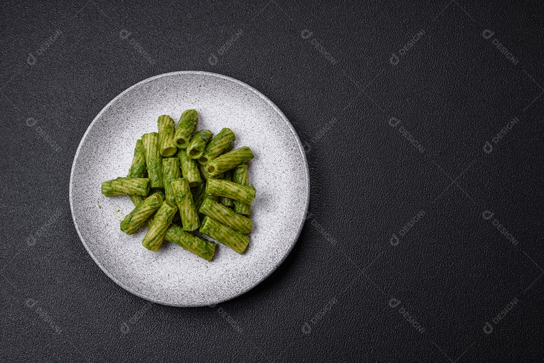Deliciosa massa com molho de espinafre, azeite e queijo parmesão com sal, especiarias e ervas sobre fundo escuro de concreto
