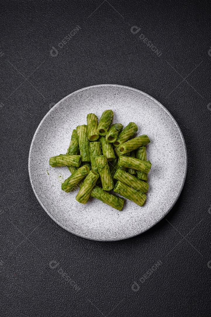Deliciosa massa com molho de espinafre, azeite e queijo parmesão com sal, especiarias e ervas sobre fundo escuro de concreto
