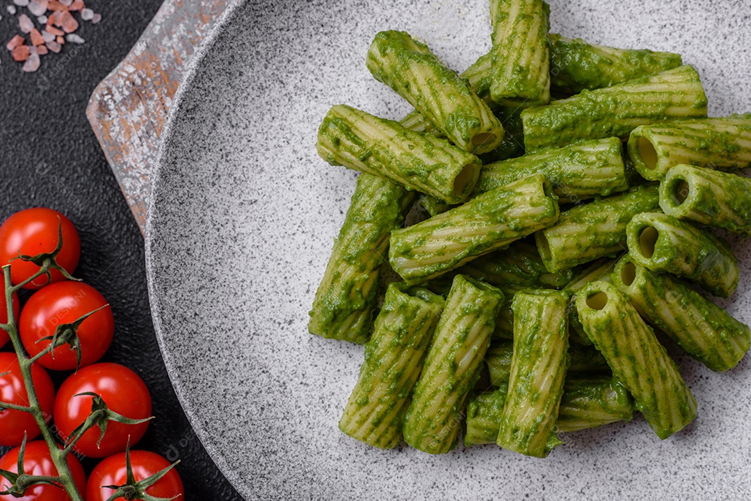 Deliciosa massa com molho de espinafre, azeite e queijo parmesão com sal, especiarias e ervas sobre fundo escuro de concreto