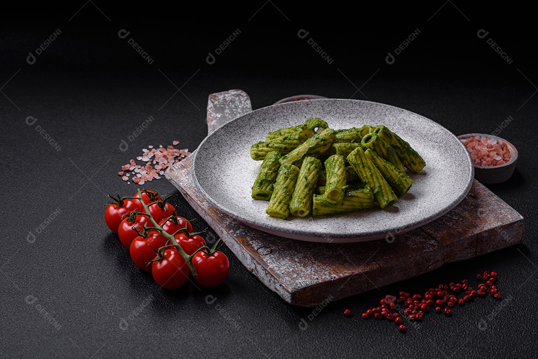 Deliciosa massa com molho de espinafre, azeite e queijo parmesão com sal, especiarias e ervas sobre fundo escuro de concreto