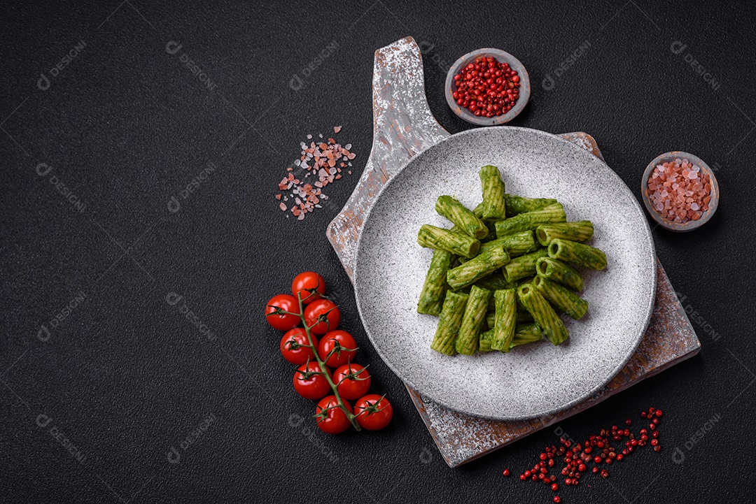 Deliciosa massa com molho de espinafre, azeite e queijo parmesão com sal, especiarias e ervas sobre fundo escuro de concreto