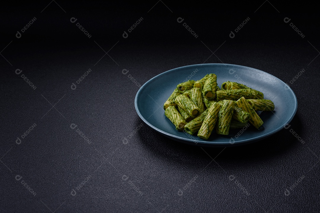 Deliciosa massa com molho de espinafre, azeite e queijo parmesão com sal, especiarias e ervas sobre fundo escuro de concreto