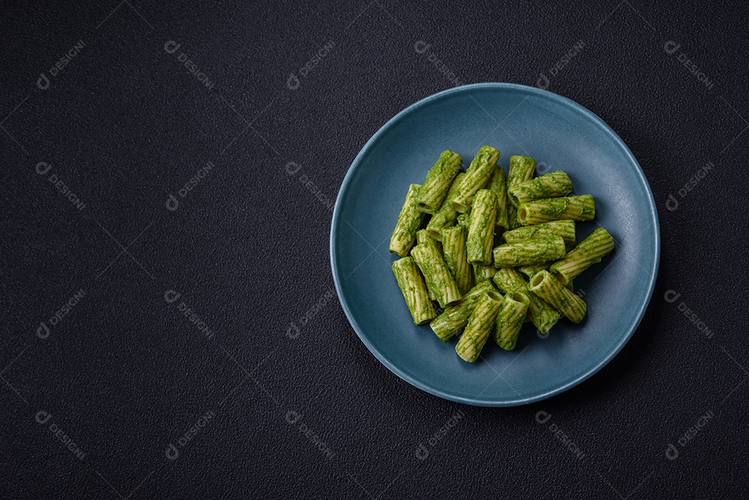 Deliciosa massa com molho de espinafre, azeite e queijo parmesão com sal, especiarias e ervas sobre fundo escuro de concreto