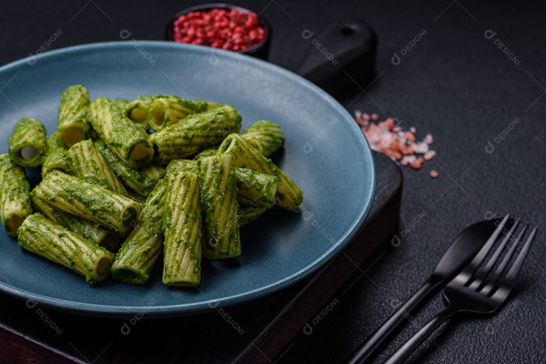 Deliciosa massa com molho de espinafre, azeite e queijo parmesão com sal, especiarias e ervas sobre fundo escuro de concreto