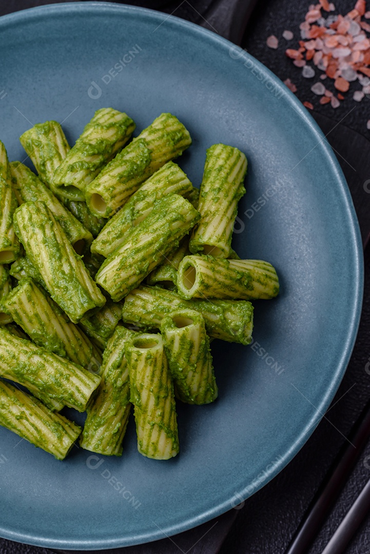Deliciosa massa com molho de espinafre, azeite e queijo parmesão com sal, especiarias e ervas sobre fundo escuro de concreto