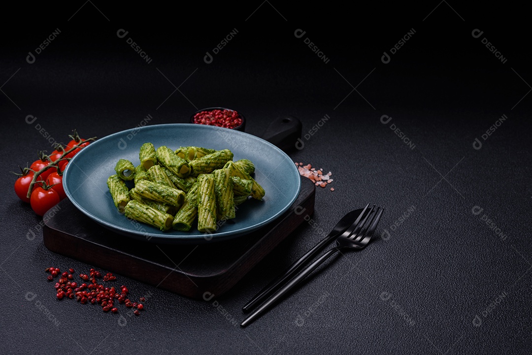 Deliciosa massa com molho de espinafre, azeite e queijo parmesão com sal, especiarias e ervas sobre fundo escuro de concreto