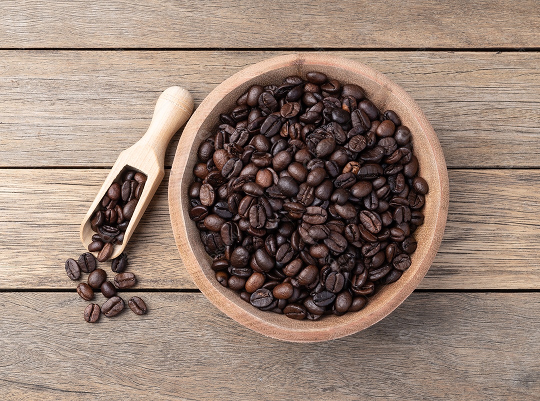Tigela e colher de madeira cheia de grãos de café