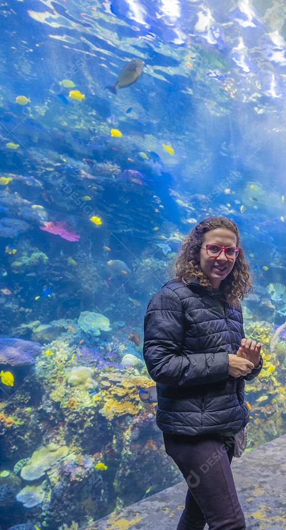 Jovem olhando e desfrutando de um grande aquário de água salgada